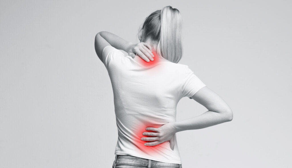 Woman with neck and back pain, rubbing her painful body, back view, panorama